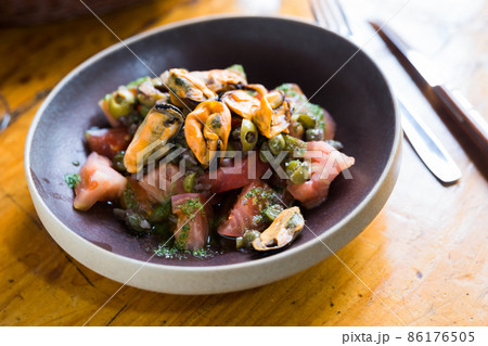 Tomatoes with arugula pesto and mussels served on a plate 86176505