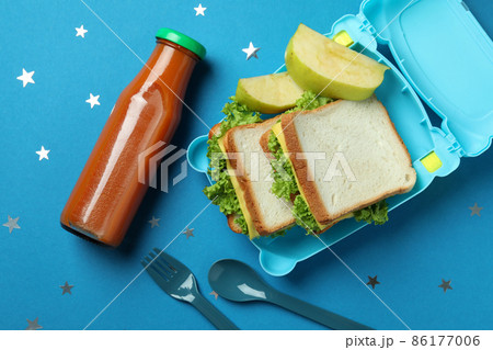 Lunch box with tasty food on blue background Lunch box with tasty food on blue background 86177006