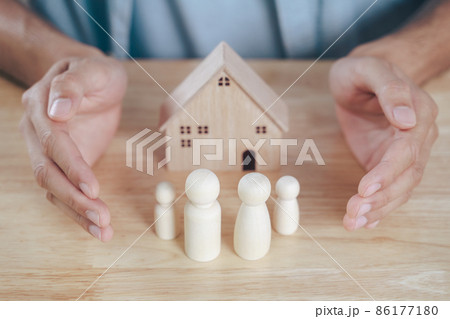 The man Hands protect over wooden peg dolls. planning, saving family, health care and insurance, family mental health, international day of families. The man Hands protect over wooden peg dolls. planning, saving family, health care and insurance, family mental health, international day of families. 86177180
