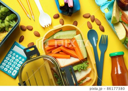 Concept of tasty eating with lunch boxes on yellow background 86177380
