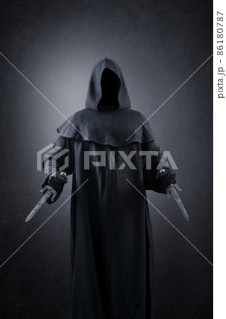 Hooded assassin with two daggers in the dark 86180787