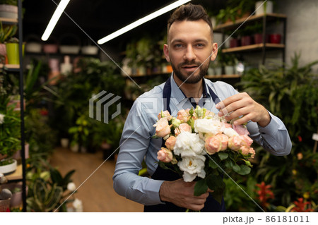 a man in an apron with a bouquet of flowers in front of a garden shop 86181011