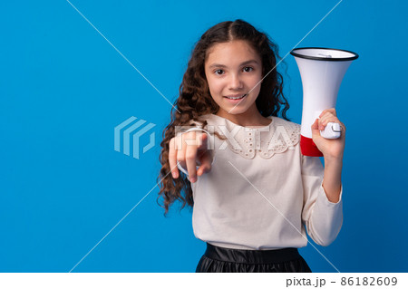 Cute schoolgirl holding megaphone against blue background 86182609