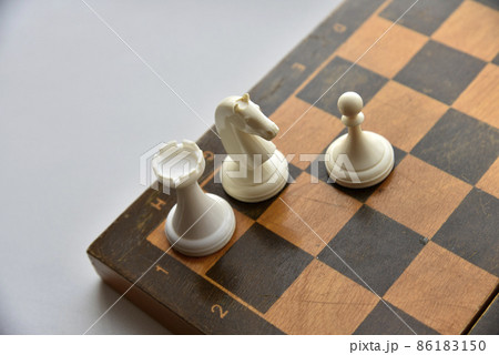 An old chessboard with white and black pieces 86183150