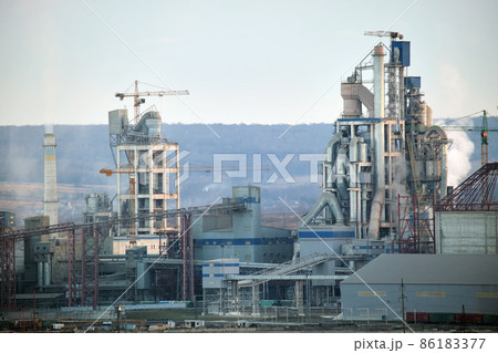 Cement plant with high factory structure and tower cranes at industrial production area. Manufacture and global industry concept Cement plant with high factory structure and tower cranes at industrial production area. Manufacture and global industry concept 86183377