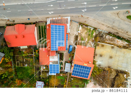 Aerial view of residential houses with rooftops covered with solar photovoltaic panels in suburban rural area 86184111