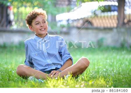 Young happy child boy relaxing on green grass in summer park. Positive kid enjoying summertime outdoors. Child wellbeing concept Young happy child boy relaxing on green grass in summer park. Positive kid enjoying summertime outdoors. Child wellbeing concept 86184160