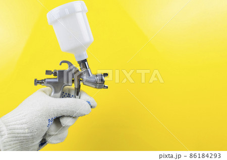 Manual and paint spray gun at work on a yellow background Manual and paint spray gun at work on a yellow background 86184293