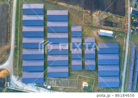 Aerial view of large sustainable electrical power plant with rows of solar photovoltaic panels for producing clean ecological electric energy. Renewable electricity with zero emission concept. Aerial view of large sustainable electrical power plant with rows of solar photovoltaic panels for producing clean ecological electric energy. Renewable electricity with zero emission concept. 86184656