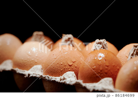 Eggs covered with water drops close up in egg protective container on black background. Foreground and background in blur. Focus in the center. 86184699