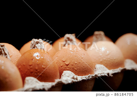 Wet eggs in a protective container on black background. Foreground and background in blur. 86184705