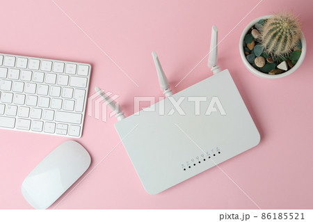 Workplace with Wi - fi router on pink background 86185521