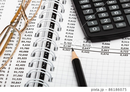 Financial report, pencil, calculator, glasses and paper with numbers on the table in the office. A paper sheet full of business data. Accounts number and the data. Business documents. Close-up 86186075
