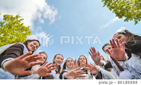 Happy Russian female graduates hug and wave their hands on graduation day. Happy Russian female graduates hug and wave their hands on graduation day. 86186888