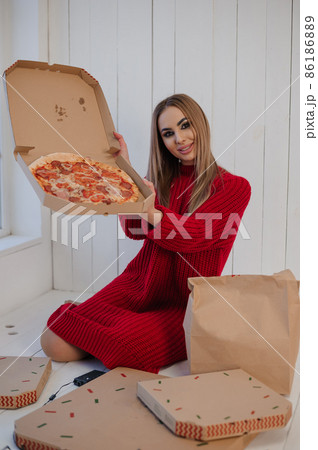 Girl in a red dress holding a pizza Girl in a red dress holding a pizza 86186889