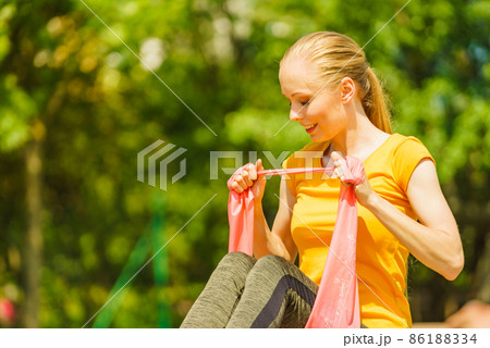 Girl doing exercise outdoor, using resistance fit band. 86188334