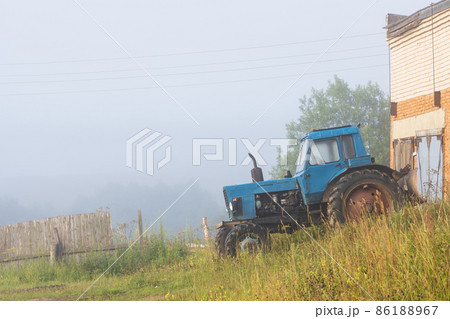 Old blue agricultural tractor near a brick building 86188967
