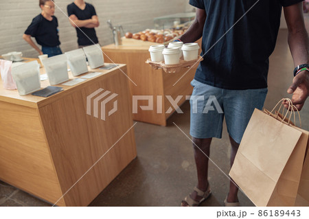 Negro courier holding grocery bags and cups of tea Negro courier holding grocery bags and cups of tea 86189443