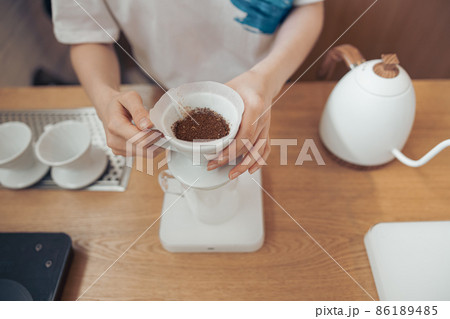 Female hands holding cup of coffee with paper filter Female hands holding cup of coffee with paper filter 86189485
