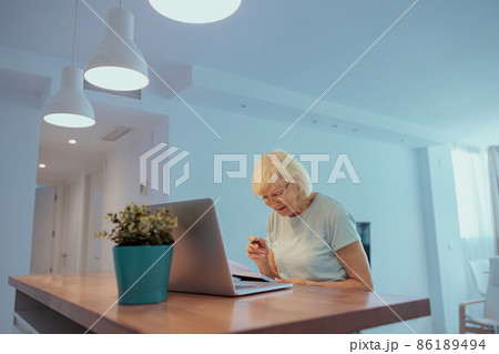 Senior woman using laptop while sitting at home Senior woman using laptop while sitting at home 86189494
