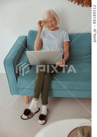 Pensioner female sitting on sofa at home 86189512
