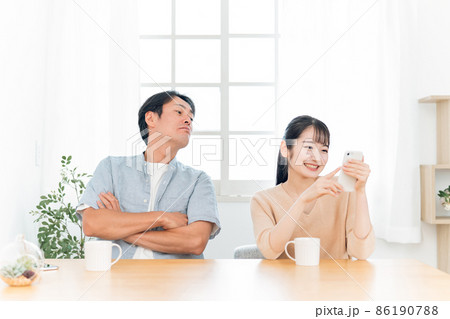 女性のスマホをのぞく男性（怒る） 86190788
