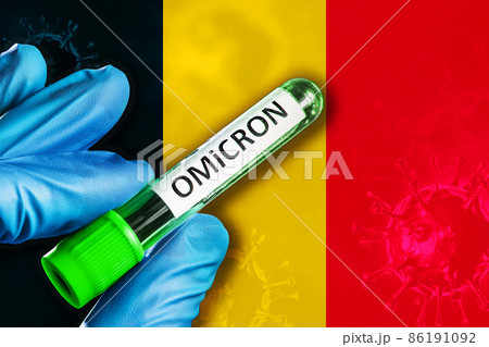 Belgium outbreak of omicron variant. Hand holds a test tube with covid-19 virus omicron in front of Belgium flag 86191092
