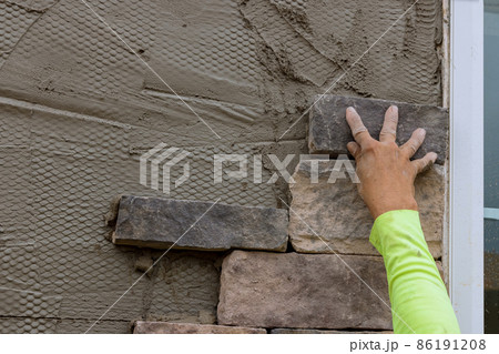 Man making texture of wall facing with decorative stone tiles bricks 86191208