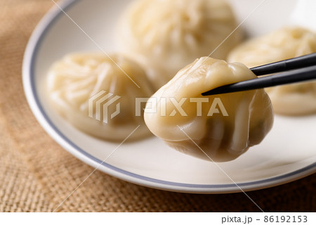 Xiao long bao, small Chinese steamed bun filling with minced pork eating by use chopsticks Xiao long bao, small Chinese steamed bun filling with minced pork eating by use chopsticks 86192153