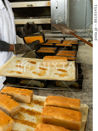 Baker hands with potholder next to metal cookie sheet with bread in oven 86193451