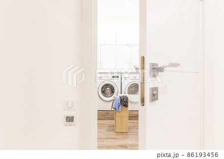 View through door to laundry room with basket and washing machine 86193456