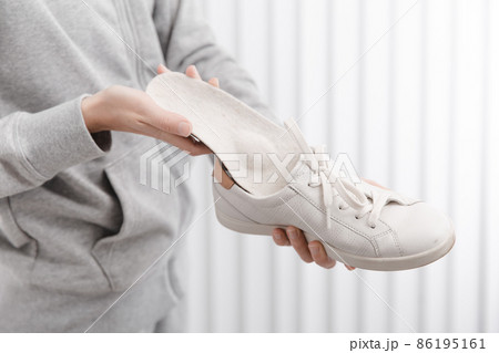 Woman putting orthopedic insole into shoe at home. Sports girl fitting orthopedic insole indoors, close up. Foot care banner. Flat Feet Correction. Treatment and prevention of foot diseases. Woman putting orthopedic insole into shoe at home. Sports girl fitting orthopedic insole indoors, close up. Foot care banner. Flat Feet Correction. Treatment and prevention of foot diseases. 86195161