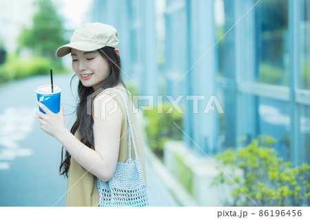 アイスコーヒーを飲みながら歩く女性 86196456