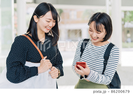 キャンパスでスマホを見る女子大学生 86200679