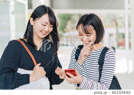 キャンパスでスマホを見る女子大学生 キャンパスでスマホを見る女子大学生 86200680