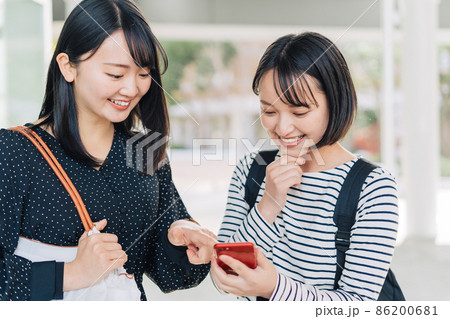 キャンパスでスマホを見る女子大学生 キャンパスでスマホを見る女子大学生 86200681