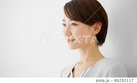 白壁を背にして笑顔で立つビジネスウーマン 86202117