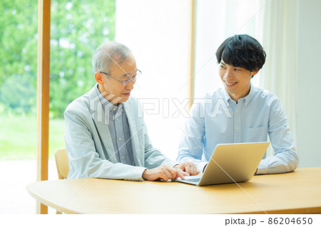 シニア男性とパソコンを見る若い男性 シニア男性とパソコンを見る若い男性 86204650