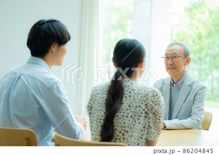 会話するシニア男性と若い夫婦 86204845