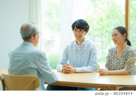 会話するシニア男性と若い夫婦 86204854