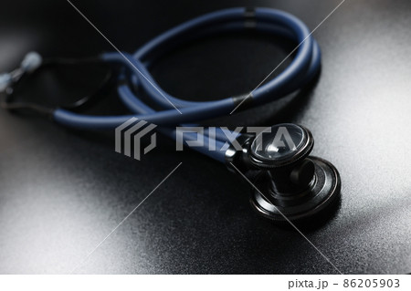 Doctor stethoscope equipment on dark surface, tool for patient diagnostic 86205903