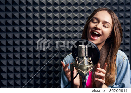 Teen girl in recording studio with mic over acoustic absorber panel background 86206811