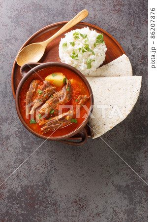 Guatemalan Shredded Beef Stew served with rice and tortilla close-up in a plate. Vertical top view 86207876