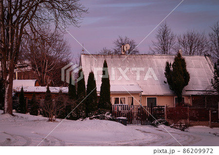 House with firs and fence in pinkish blue sunset in winter 86209972