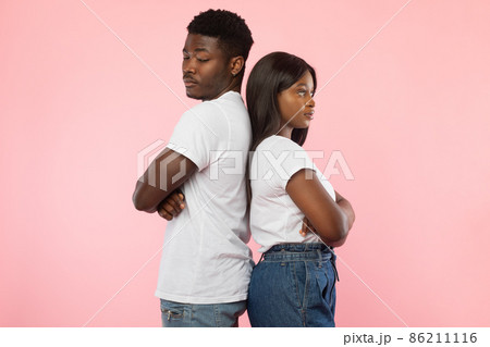 Black couple standing back to back, pink studio wall 86211116