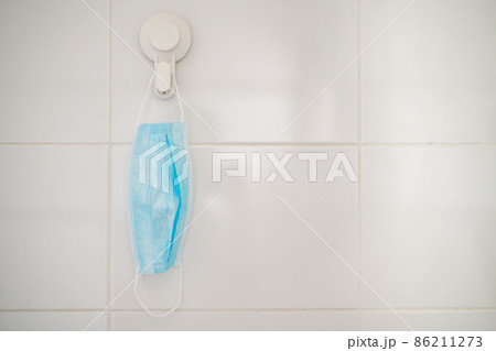 Used protective face mask hanging over the door knob. Used protective face mask hanging over the door knob. 86211273