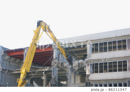 老朽化した公共建造物の解体作業をする重機 86211347