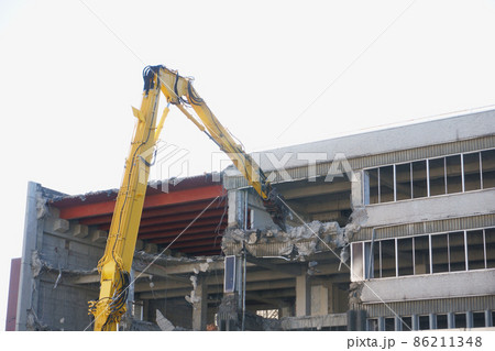 老朽化した公共建造物の解体作業をする重機 86211348