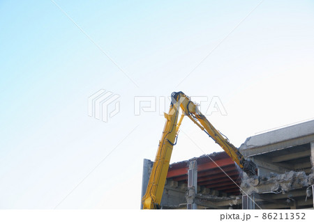 老朽化した公共建造物の解体作業をする重機 86211352