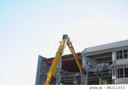 老朽化した公共建造物の解体作業をする重機 86211353